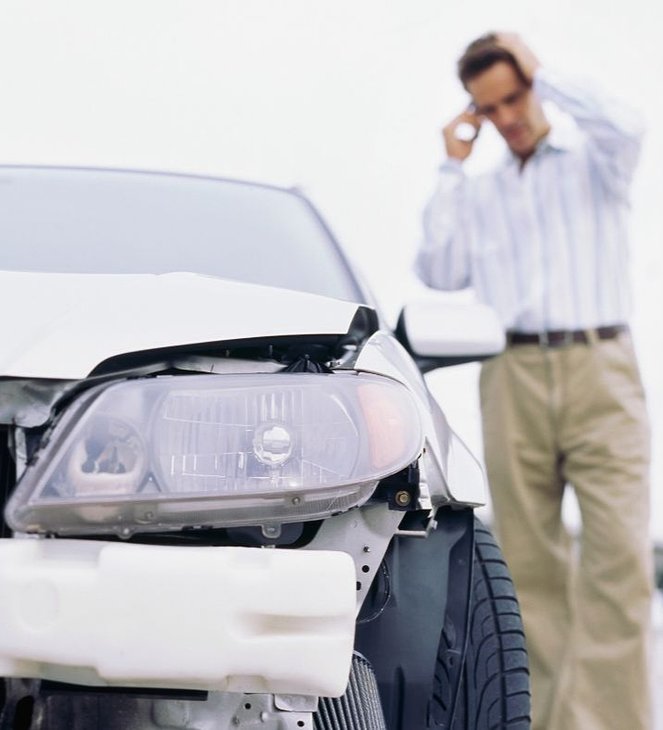 wrecked car and a man on the phone